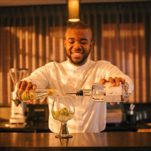 A barman pouring a gin and tonic at Sanctuary Mandela's bar and lounge