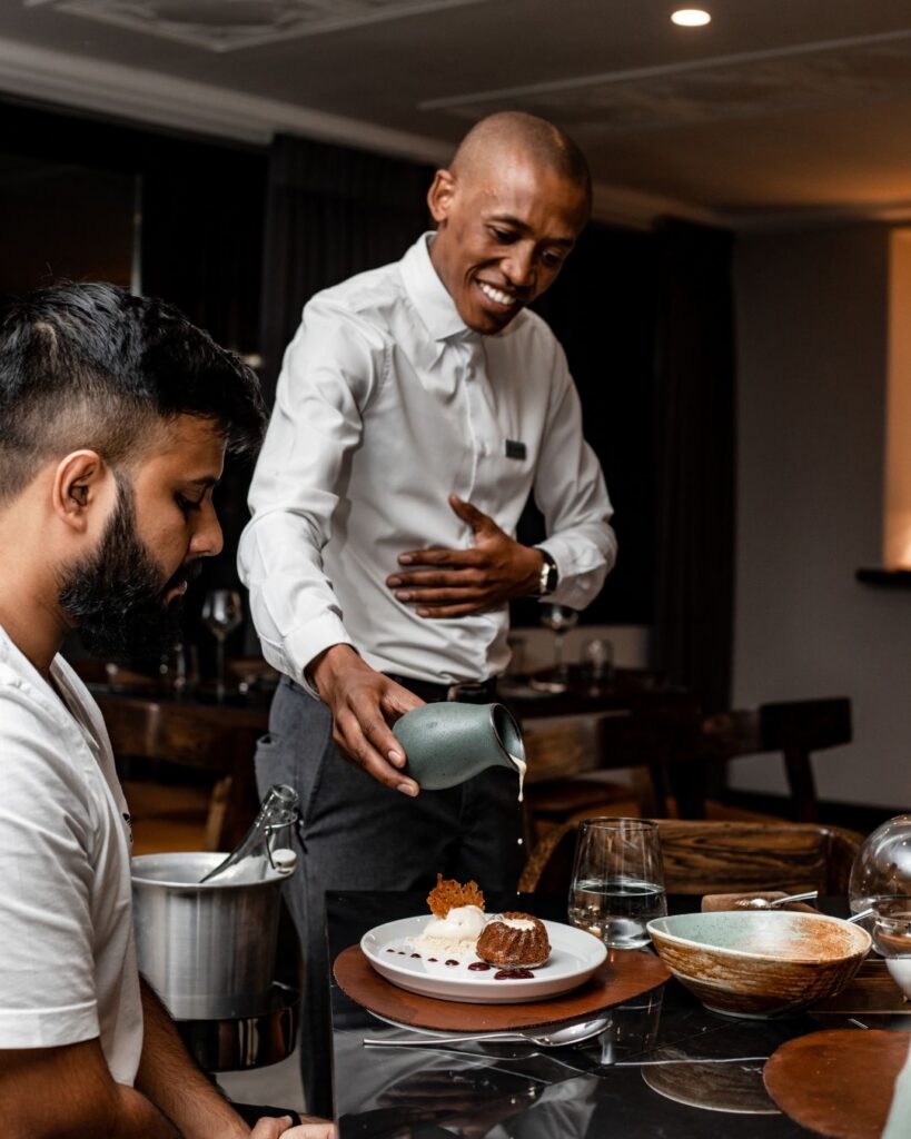 A waiter serving dessert to a guest at Insights Restaurant at Sanctuary Mandela